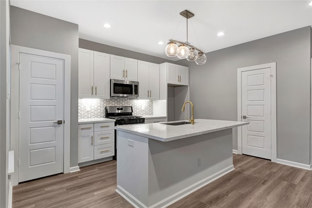 kitchen featuring sink, stainless steel appliances, light hardwood / wood-style flooring, an island with sink, and white cabinets