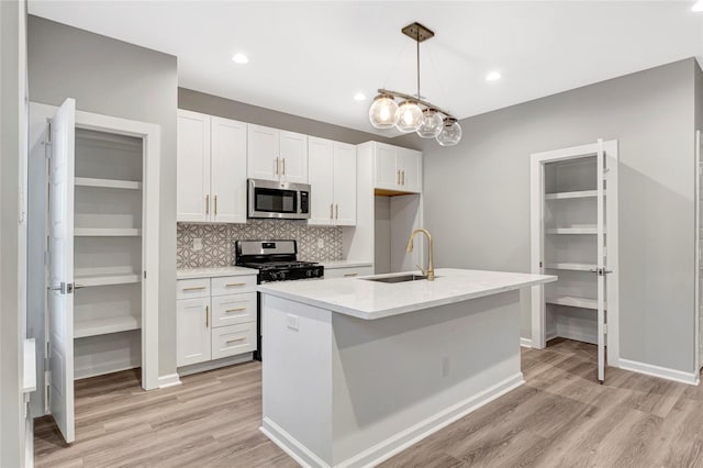 kitchen with sink, an island with sink, decorative light fixtures, white cabinetry, and stainless steel appliances