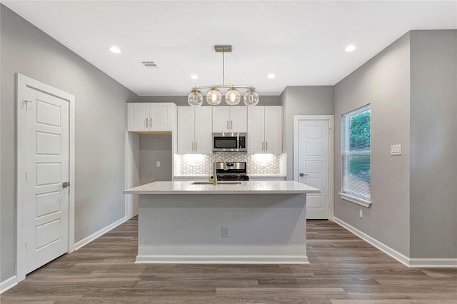 kitchen featuring sink, white cabinetry, stainless steel appliances, and an island with sink