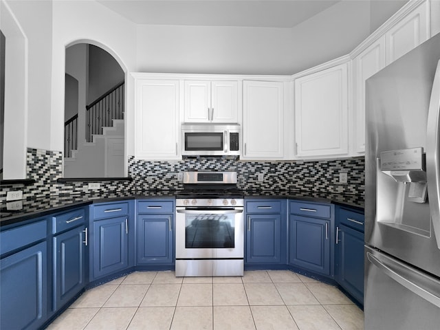 kitchen featuring decorative backsplash, white cabinetry, blue cabinets, and appliances with stainless steel finishes