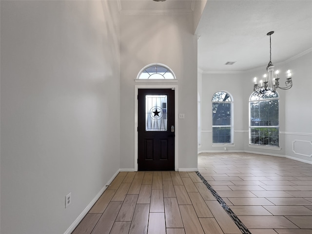 entrance foyer featuring a chandelier, hardwood / wood-style floors, ornamental molding, and a high ceiling