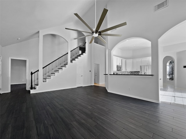 unfurnished living room with dark hardwood / wood-style floors, ceiling fan, and high vaulted ceiling