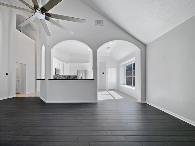 unfurnished living room with a textured ceiling, high vaulted ceiling, and dark wood-type flooring