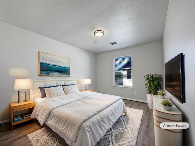 bedroom with a textured ceiling and dark hardwood / wood-style flooring