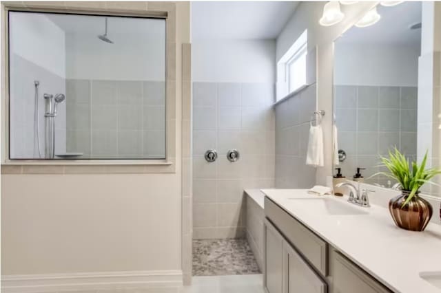 bathroom featuring tile patterned flooring, vanity, tiled shower, and tile walls