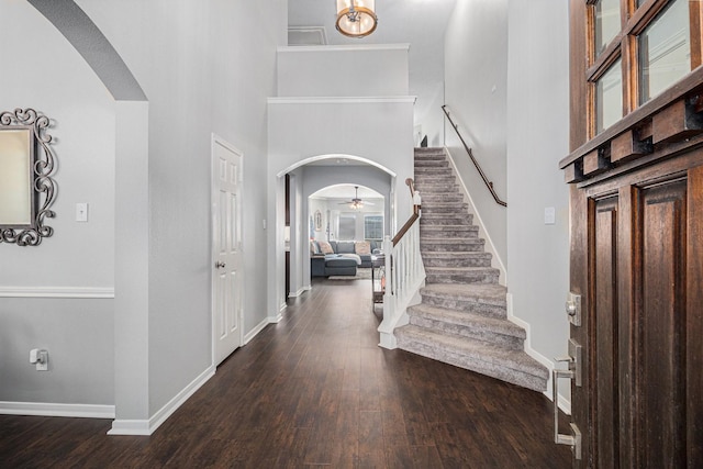 entryway featuring ceiling fan, dark wood-type flooring, and a high ceiling