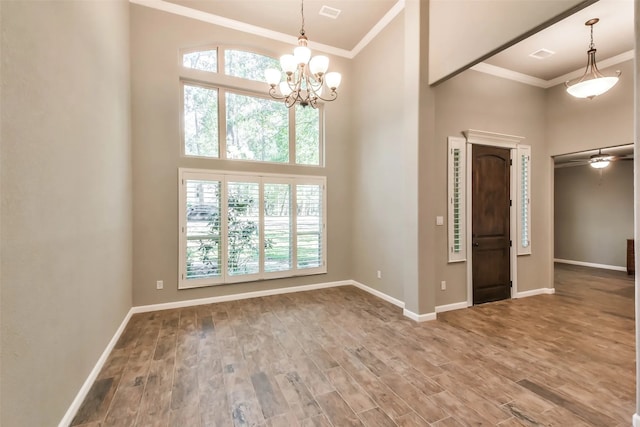 empty room with a towering ceiling, hardwood / wood-style flooring, and ornamental molding