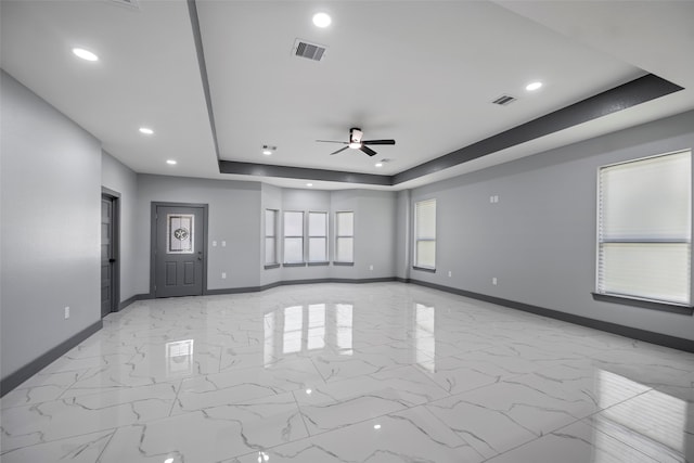 empty room featuring a tray ceiling and ceiling fan