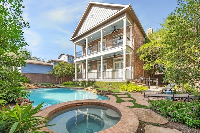 rear view of house with a pool with hot tub, a balcony, a patio, and ceiling fan