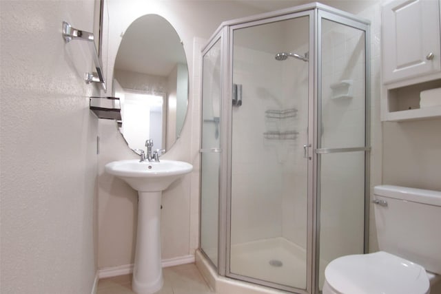 bathroom with tile patterned flooring, toilet, and a shower with shower door