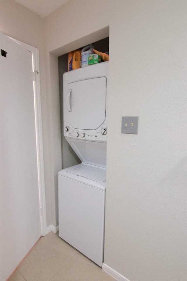 laundry area featuring light tile patterned floors and stacked washer / dryer