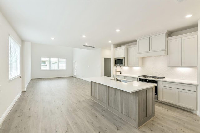 16334 Placid Stream St, Conroe, TX 77302 - kitchen with a sink, light wood-style floors, a kitchen island with sink, stainless steel appliances, and light countertops