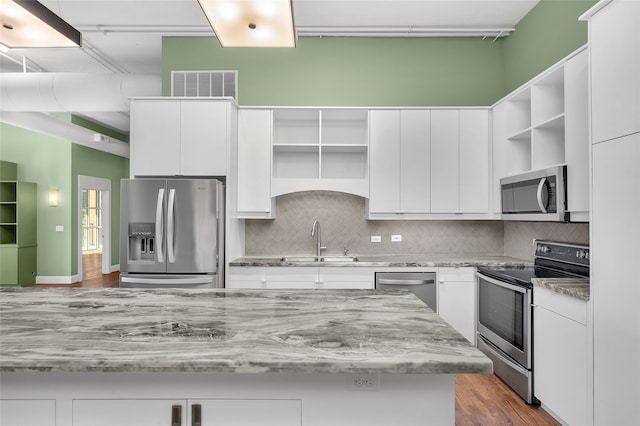 kitchen with decorative backsplash, appliances with stainless steel finishes, sink, wood-type flooring, and white cabinets