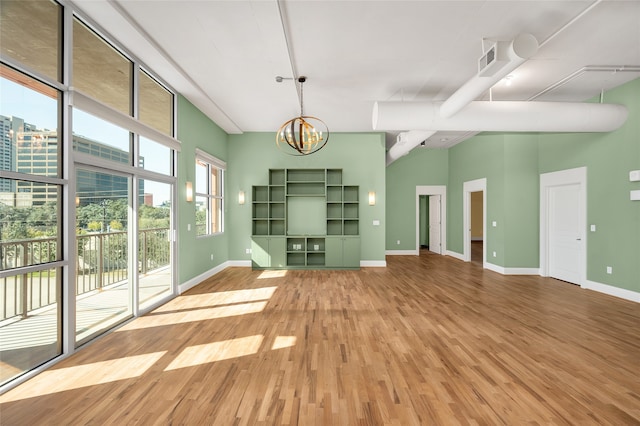 unfurnished living room featuring wood-type flooring and an inviting chandelier