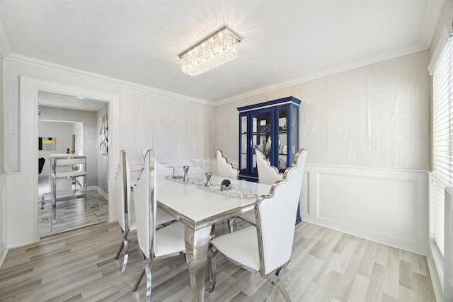 dining room featuring a chandelier, light hardwood / wood-style flooring, and crown molding