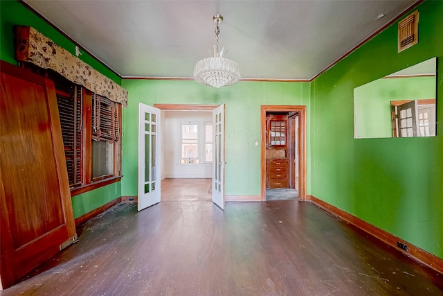 spare room featuring dark hardwood / wood-style floors, french doors, crown molding, and a chandelier