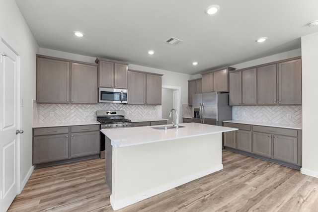 kitchen featuring appliances with stainless steel finishes, tasteful backsplash, light hardwood / wood-style flooring, and sink