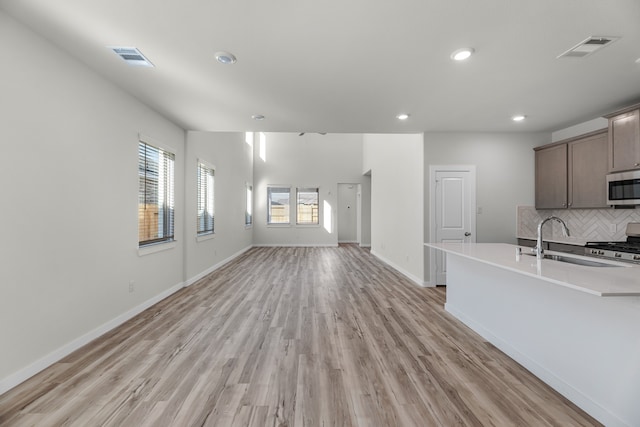 kitchen featuring backsplash, stainless steel appliances, light hardwood / wood-style flooring, and sink