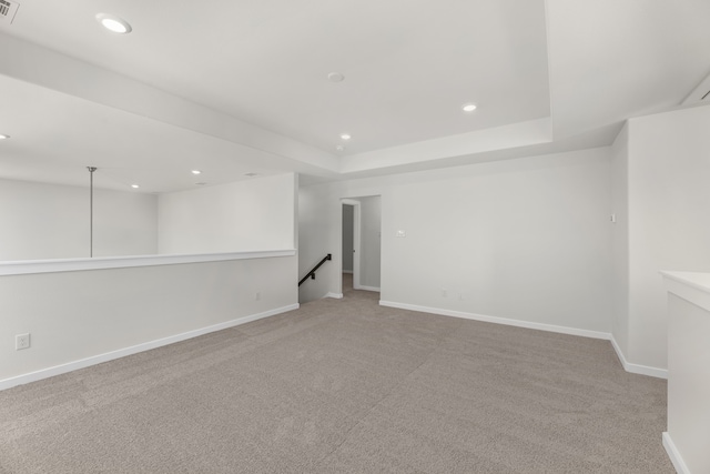 empty room featuring light carpet and a raised ceiling