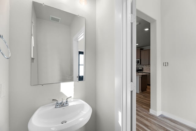 bathroom with decorative backsplash, hardwood / wood-style flooring, and sink