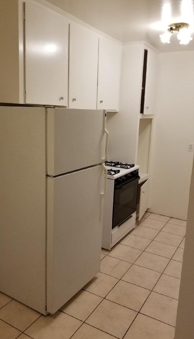 kitchen featuring light tile patterned floors, white cabinets, and white appliances