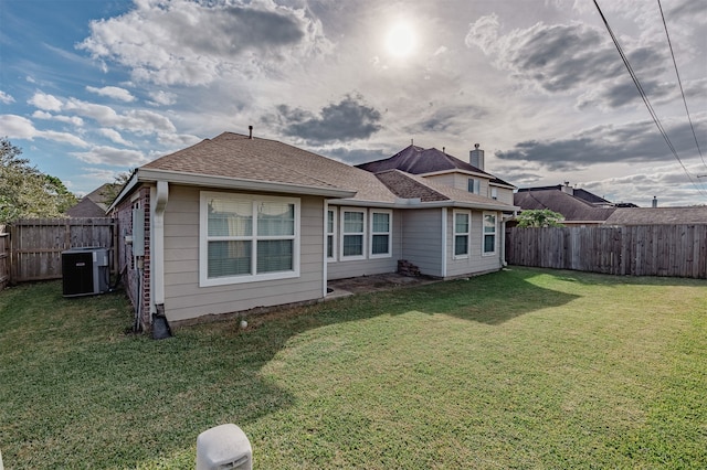 back of property featuring central air condition unit and a lawn