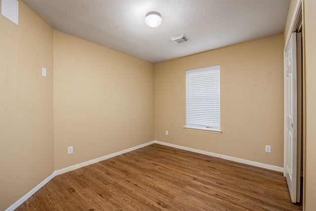 empty room with a textured ceiling and hardwood / wood-style flooring