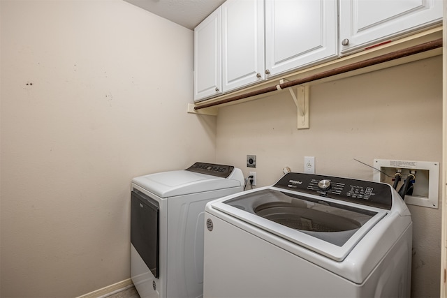 washroom with cabinets, a textured ceiling, and washing machine and dryer