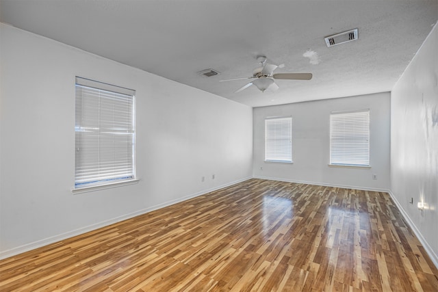 empty room with ceiling fan, light hardwood / wood-style floors, and a textured ceiling