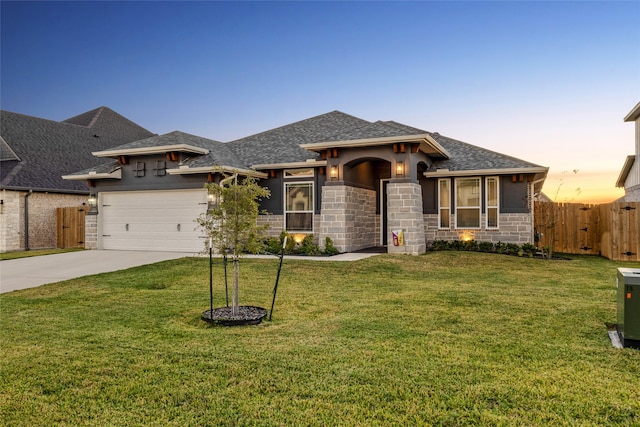 prairie-style house featuring a yard, central AC unit, and a garage