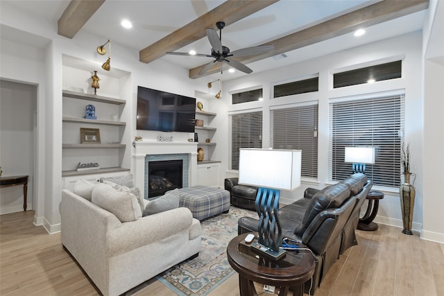 living room featuring beam ceiling, ceiling fan, built in features, and light wood-type flooring