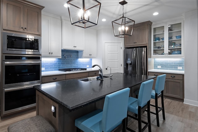 kitchen featuring a kitchen breakfast bar, a chandelier, a center island with sink, white cabinets, and appliances with stainless steel finishes