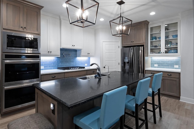 3509 Castine Ct, Bryan, TX 77808 - kitchen with stainless steel appliances, a chandelier, backsplash, glass insert cabinets, and light wood finished floors
