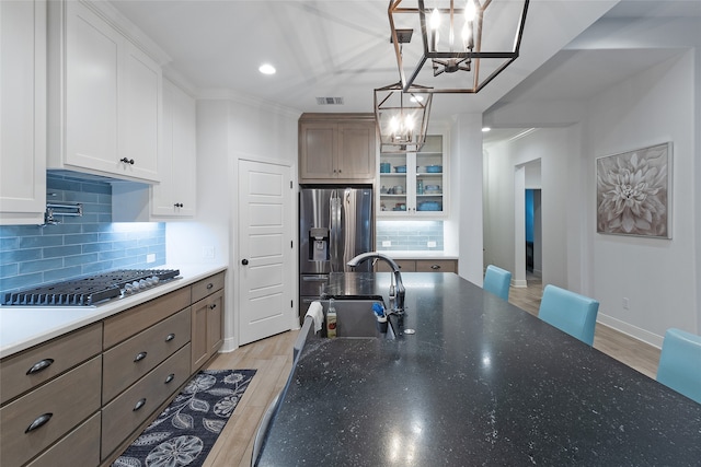 kitchen featuring white cabinets, sink, appliances with stainless steel finishes, a notable chandelier, and light hardwood / wood-style floors