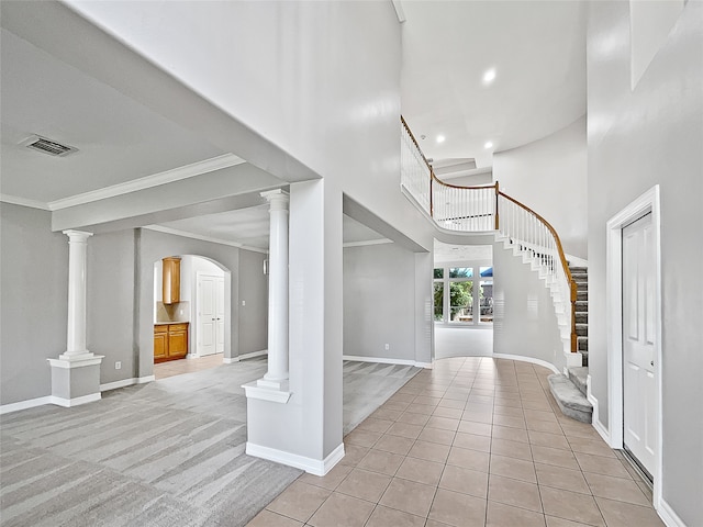 tiled foyer entrance featuring crown molding and a towering ceiling