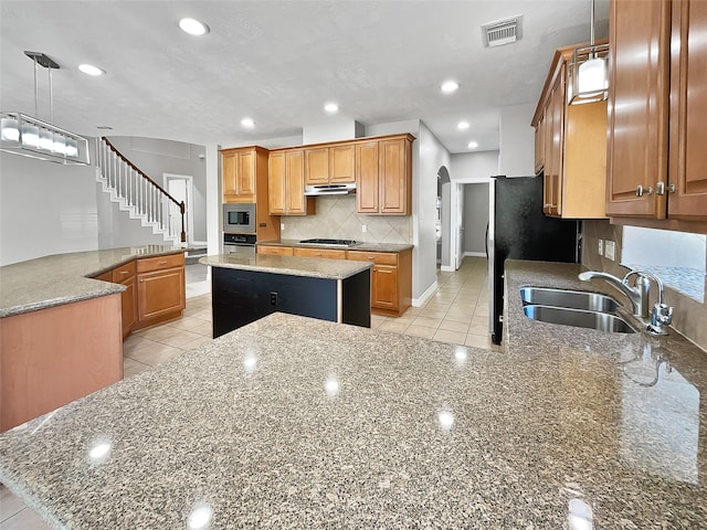 kitchen featuring light stone counters, kitchen peninsula, pendant lighting, a kitchen island, and appliances with stainless steel finishes