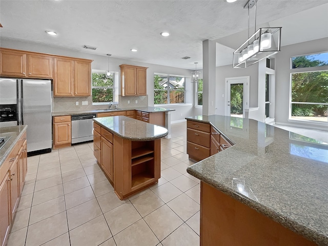 kitchen with stone counters, pendant lighting, a kitchen island, and stainless steel appliances