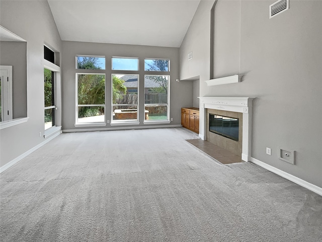 unfurnished living room with a fireplace, light carpet, and high vaulted ceiling