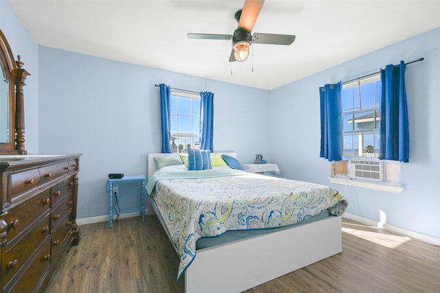 bedroom featuring multiple windows, ceiling fan, cooling unit, and dark wood-type flooring