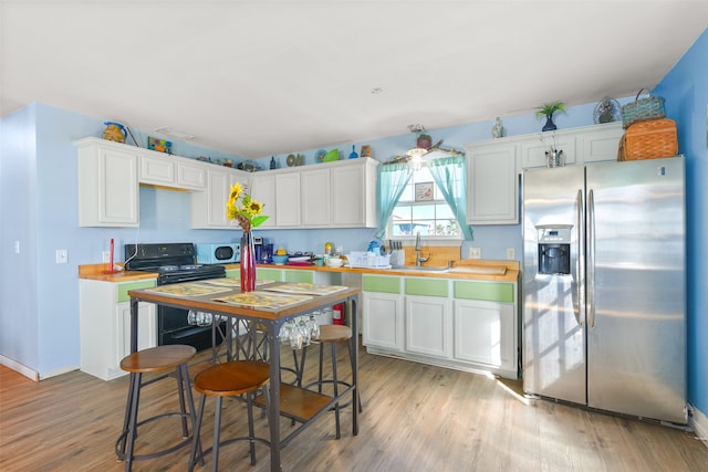 kitchen featuring white cabinets, stainless steel fridge with ice dispenser, light hardwood / wood-style flooring, and black range with electric stovetop