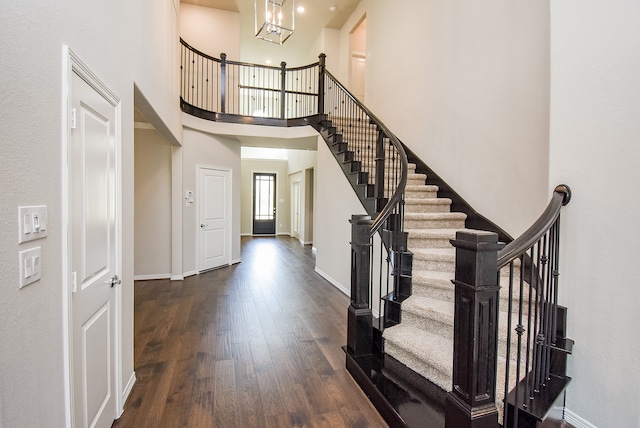 foyer entrance with dark hardwood / wood-style flooring, a towering ceiling, and a chandelier