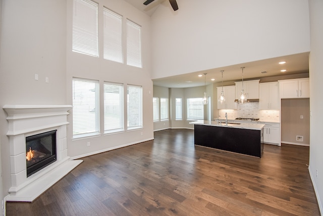 living room with dark hardwood / wood-style floors, ceiling fan, a towering ceiling, and sink