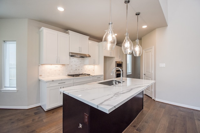 kitchen featuring white cabinets, dark hardwood / wood-style flooring, an island with sink, and decorative light fixtures