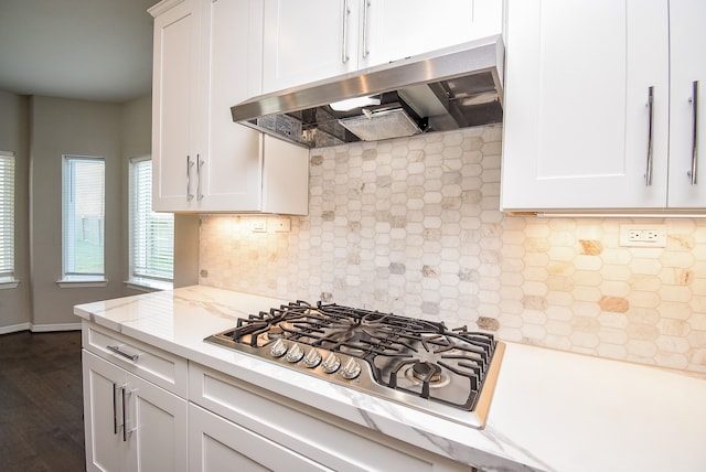 kitchen with light stone countertops, dark hardwood / wood-style flooring, tasteful backsplash, white cabinets, and stainless steel gas stovetop