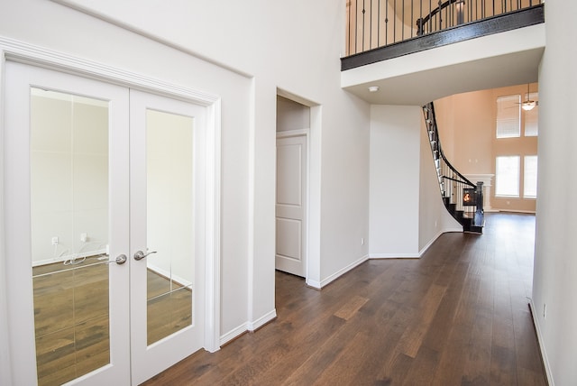 hall featuring dark hardwood / wood-style floors, a towering ceiling, and french doors