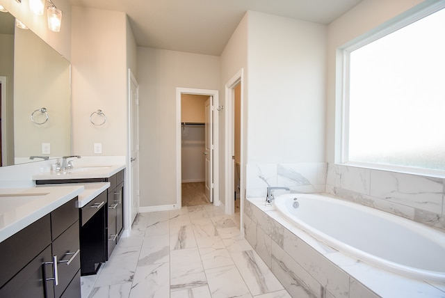 bathroom featuring tiled tub and vanity