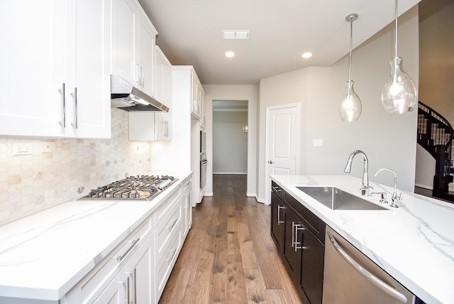 kitchen with white cabinets, hanging light fixtures, sink, appliances with stainless steel finishes, and dark hardwood / wood-style flooring