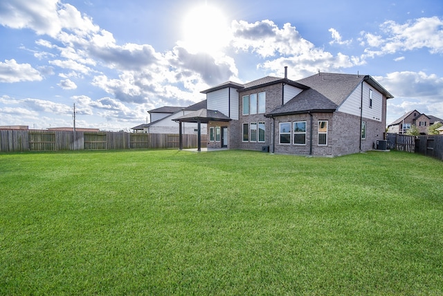 rear view of house with central AC and a yard