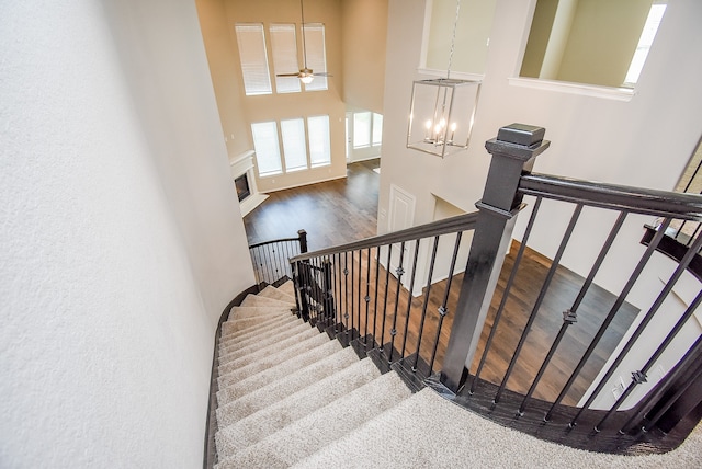 stairs featuring ceiling fan with notable chandelier and hardwood / wood-style flooring