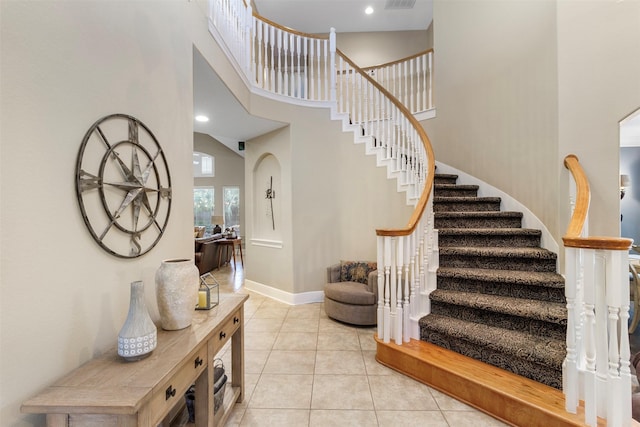 stairway with tile patterned flooring and a towering ceiling